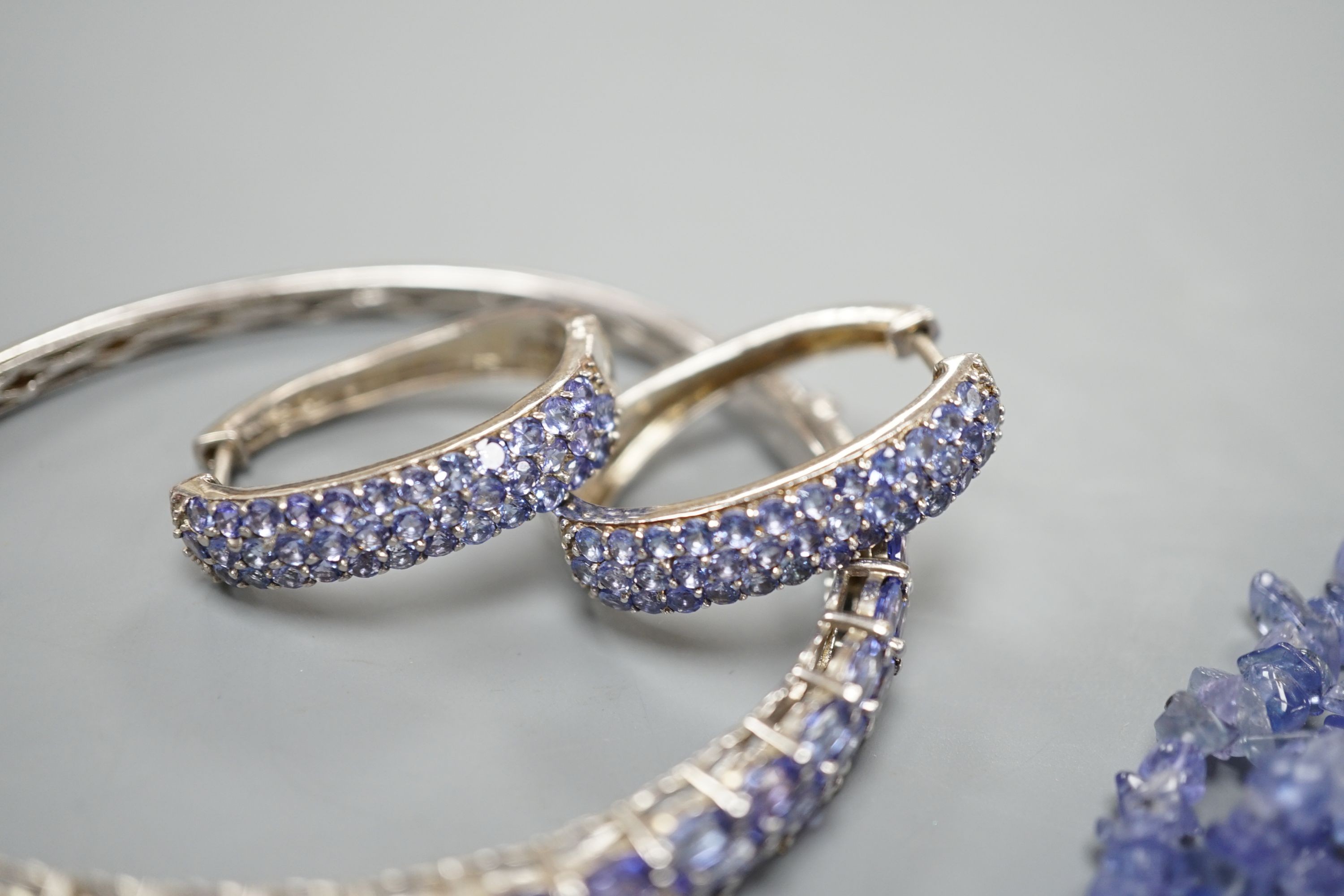 A modern 925 and tanzanite set hinged bangle, a similar pair of earrings and pendant and a rough cut tanzanite set necklace.